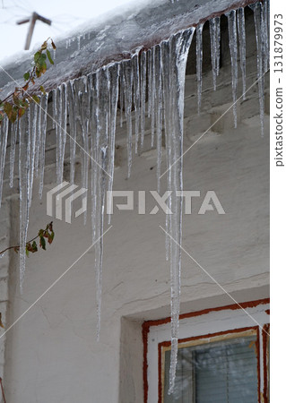 Large long icicles hang from roof of house 131879973