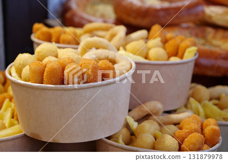Fried potatoes, cheese fried balls and other baked goods in large paper bowls 131879978