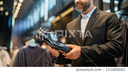 Leather footwear. Shop assistant man in shoe store hold classic footwear. Shoe store. Business man choose elegant footwear in shop. Classic leather shoes for formal look. Formal shoe. Choosing size 131880083