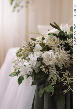 Elegant floral wedding decoration with white roses and greenery on beige curtain background 131880163