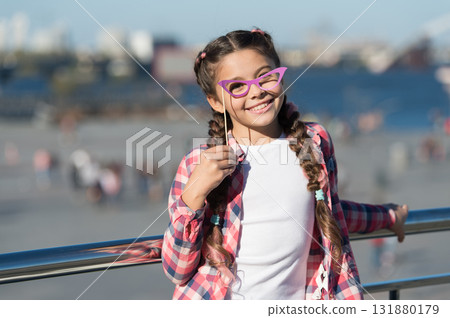 Choosing prop goggles perfect for her style. Little child looking through fancy goggles on urban background. Small girl holding goggles fashion accessory. Adorable kid with goggles for photobooth fun Choosing prop goggles perfect for her style. Little child looking through fancy goggles on urban background. Small girl holding goggles fashion accessory. Adorable kid with goggles for photobooth fun 131880179