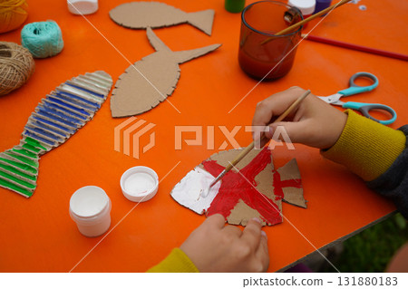 Build a fish sculpture from cardboard materials, thread, and paint, with step-by-step guidance, on an orange background. 131880183