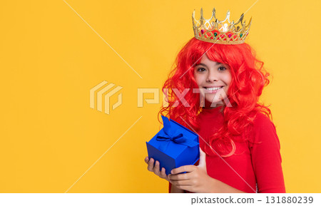positive girl in crown with present box on yellow background positive girl in crown with present box on yellow background 131880239