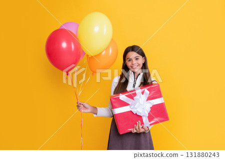 smiling child with party colorful balloons and present box on yellow background 131880243