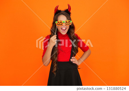 Girl devil in Halloween costume isolated on orange. Trick or treat. All Hallows costume party celebration. All Hallows devil. Imp horns. Girl in Halloween imp costume. Happy Halloween. Sharp horns 131880524