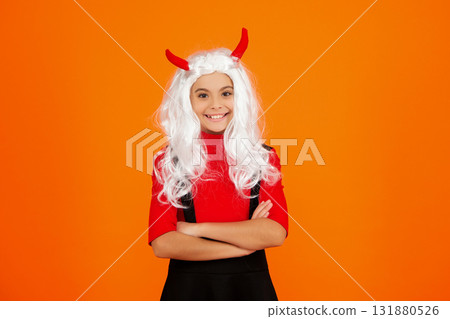 Girl devil in Halloween costume isolated on orange. Trick or treat. All Hallows costume party celebration. All Hallows devil. Imp horns. Girl in Halloween imp costume. Happy Halloween. Wicked grin 131880526
