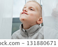 Boy looks up through light fabric, soft expression and visible chin mark intimate candid moment in calm atmosphere 131880671