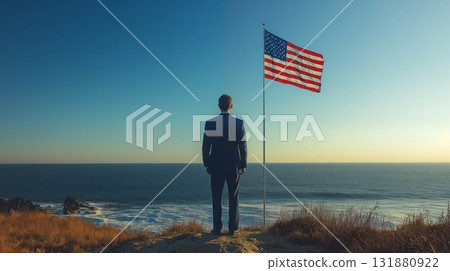 White man in business suit standing by American flag overlooking ocean, representing leadership and patriotic vision in coastal landscape 131880922
