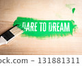 Paintbrush leaving a bold green stroke with the motivational phrase Dare to Dream on a wooden 131881311
