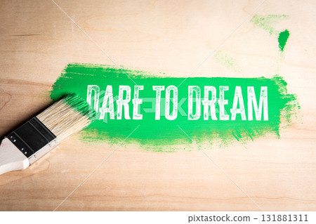 Paintbrush leaving a bold green stroke with the motivational phrase Dare to Dream on a wooden 131881311