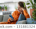 Calm middle-aged woman enveloped in state of serenity and contentment reading e-book on smartphone 131881324