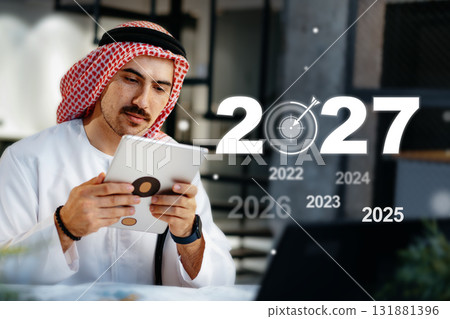 Focused businessman plans goals for the upcoming year while using a tablet 131881396