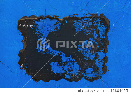 Blue Wall with Black Cracked Paint. Closeup of blue wall with peeling black paint and cracked surface. Concept of urban decay, grunge background texture, abstract background pattern 131881455