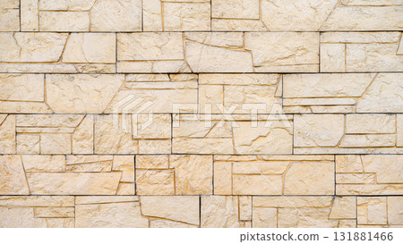 Yellow decorative stone wall with geometric blocks and detailed chiseled texture. Concept of modern architecture, structure, building aesthetics. Natural background, copy space 131881466