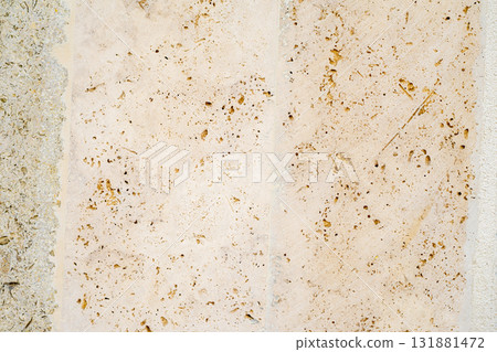 Close-up of porous beige limestone texture with fossil inclusions and weathered surface. Concept of natural erosion, geology and stone aging. Natural background, copy space Close-up of porous beige limestone texture with fossil inclusions and weathered surface. Concept of natural erosion, geology and stone aging. Natural background, copy space 131881472