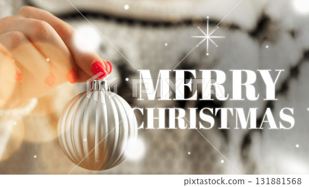 Celebratory Christmas decoration with a silver ornament held by a hand with red nails Celebratory Christmas decoration with a silver ornament held by a hand with red nails 131881568