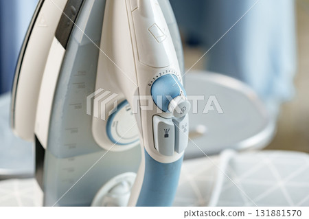 Iron positioned on an ironing board in a bright and organized laundry room during the daytime 131881570