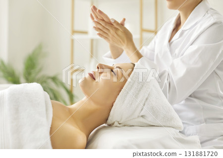 Female cosmetologist preparing for making massage to a young girl in beauty salon. Female cosmetologist preparing for making massage to a young girl in beauty salon. 131881720