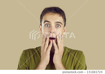 Portrait of a young surprised young boy with open mouth isolated on studio beige background. Portrait of a young surprised young boy with open mouth isolated on studio beige background. 131881724