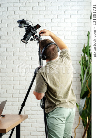 Creative professional adjusts camera setup in modern workspace for video recording 131881731
