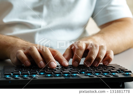 Man typing on keyboard in well-lit home office setting during daytime 131881778