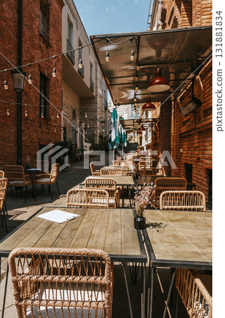 Outdoor dining area with rustic decor and string lights in urban setting during bright sunny day 131881834