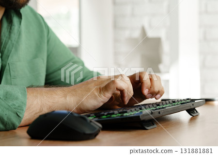 Person typing on keyboard at a desk in a bright workspace during the day Person typing on keyboard at a desk in a bright workspace during the day 131881881