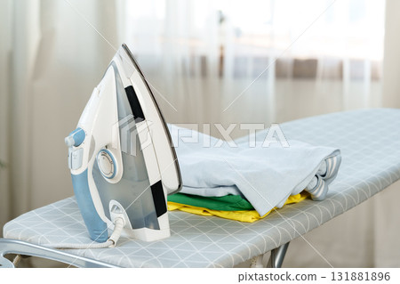 Ironing clothes on an ironing board in a bright room during the day Ironing clothes on an ironing board in a bright room during the day 131881896