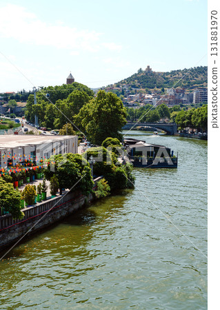 Scenic riverside view showcasing greenery and leisurely activities in a vibrant urban setting Scenic riverside view showcasing greenery and leisurely activities in a vibrant urban setting 131881970