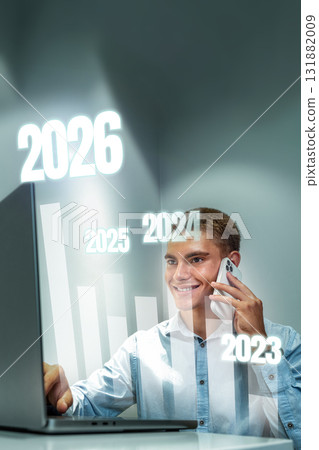 Businessman analyzing future trends while using a laptop and talking on a smartphone 131882009