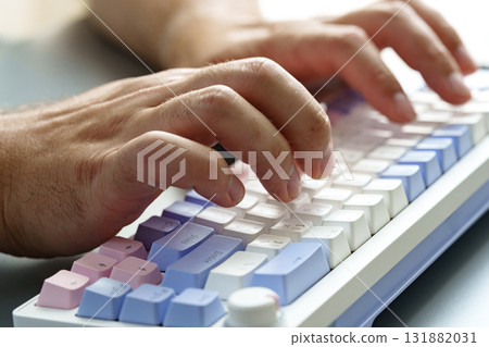 Hands typing on a colorful keyboard in a modern workspace setting during daylight hours 131882031