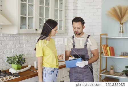 Man plumber talking with woman client signing contract for plumbing services at home. Man plumber talking with woman client signing contract for plumbing services at home. 131882085