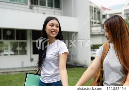 Friendship and Education. Two girls walk hand in hand, sharing a moment on campus. 131882434