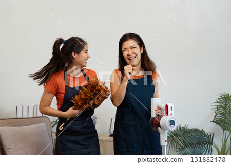 Mother and daughter joyfully cleaning together in their living room Mother and daughter joyfully cleaning together in their living room 131882478