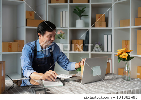 Cheerful small business owner working on a laptop and managing e-business tasks in a vibrant startup workspace 131882485