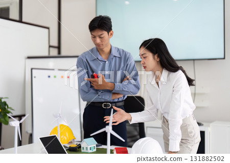 Team Collaboration on Sustainable Engineering. Engineers brainstorming solutions for eco-friendly housing designs. 131882502