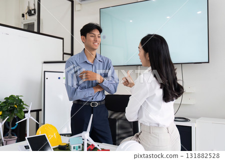 Sustainability and Engineering Networking. Two professionals conversing about renewable energy solutions in a modern office. 131882528