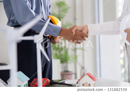 Sustainability and Engineering Collaboration. Two professionals shaking hands, acknowledging a partnership in renewable energy projects. 131882539