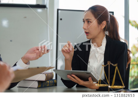 Legal Analysis and Client Interaction. A female lawyer discussing case details with a client in a professional environment. Legal Analysis and Client Interaction. A female lawyer discussing case details with a client in a professional environment. 131882653