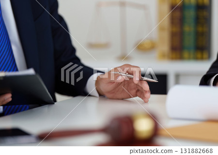 Legal Consultation and Professionalism. A lawyer reviewing documents with a pen in hand, showcasing the attention to detail required in legal practice. Legal Consultation and Professionalism. A lawyer reviewing documents with a pen in hand, showcasing the attention to detail required in legal practice. 131882668