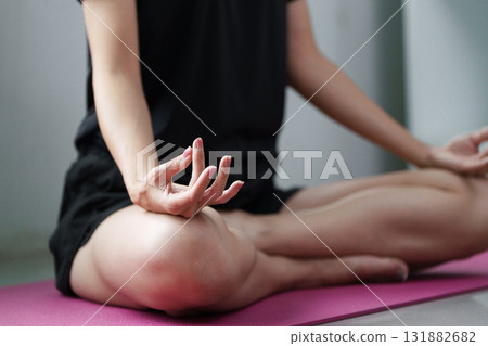 Mindfulness and Meditation. A person practicing mindfulness through yoga, sitting in a meditative pose on a yoga mat. Mindfulness and Meditation. A person practicing mindfulness through yoga, sitting in a meditative pose on a yoga mat. 131882682