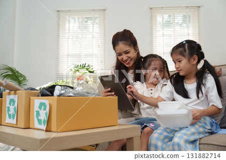 Eco-Friendly Engagement and Fun Learning. A family enjoying a recycling activity with technology. 131882714