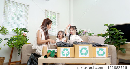 Recycling and Family Bonding. A mother and her daughters engage in a fun recycling project at home. 131882716