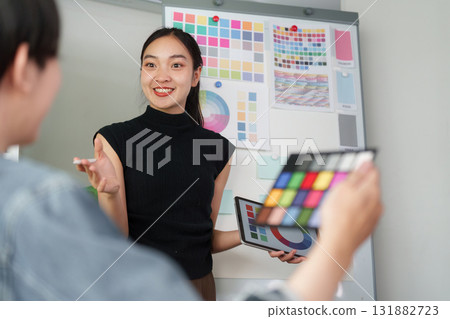 Creative Collaboration and Teamwork. UX UI designer presenting color palettes to her team during a collaborative meeting. 131882723