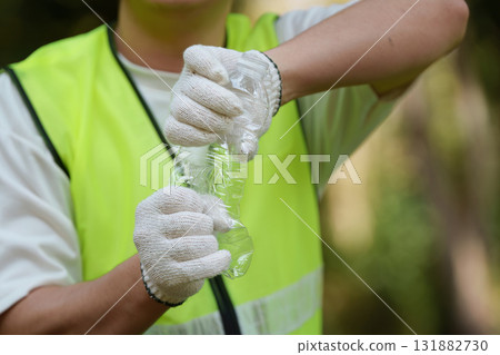 Sustainability and Volunteerism. A volunteer crushing a plastic bottle while participating in a community cleanup event. 131882730