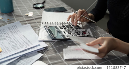 Individual calculating expenses with a calculator and receipts on a table Individual calculating expenses with a calculator and receipts on a table 131882747