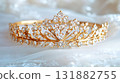 Golden Tiara Adorned with Jewels Resting on White Fabric. 131882755