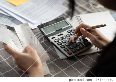 Individual calculating expenses using a calculator and receipts on a table 131882759