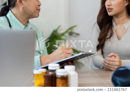 Detailed Consultation and Patient Care. The elderly doctor discussing treatment options while taking notes during a patient visit. Detailed Consultation and Patient Care. The elderly doctor discussing treatment options while taking notes during a patient visit. 131882767