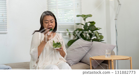 Healthy Eating and Elderly Wellness. A woman enjoying a nutritious salad, emphasizing the importance of healthy eating at home. Healthy Eating and Elderly Wellness. A woman enjoying a nutritious salad, emphasizing the importance of healthy eating at home. 131882773